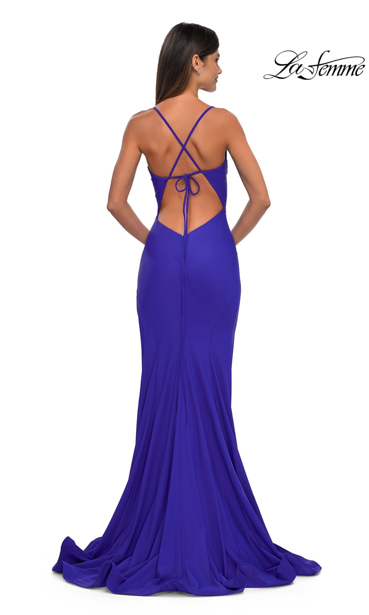 A woman in a floor-length, fitted royal blue dress with a crisscross open back and small train stands facing away, elegantly showcasing the Classic Long V-Neck Prom Dress: La Femme 33080.